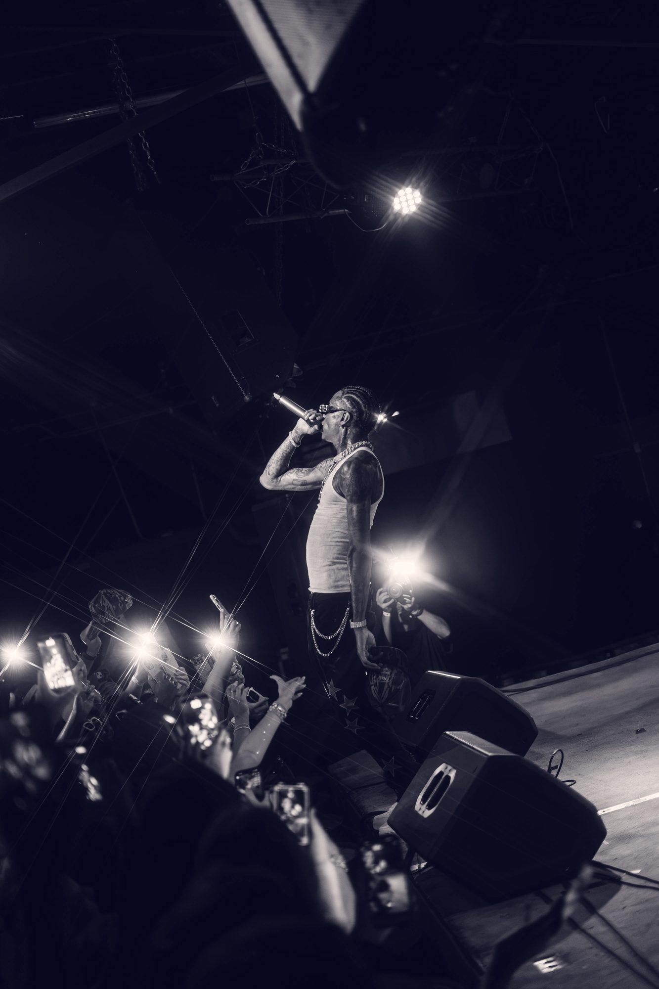 A performer at the edge of the stage, photographed from below in black and white.