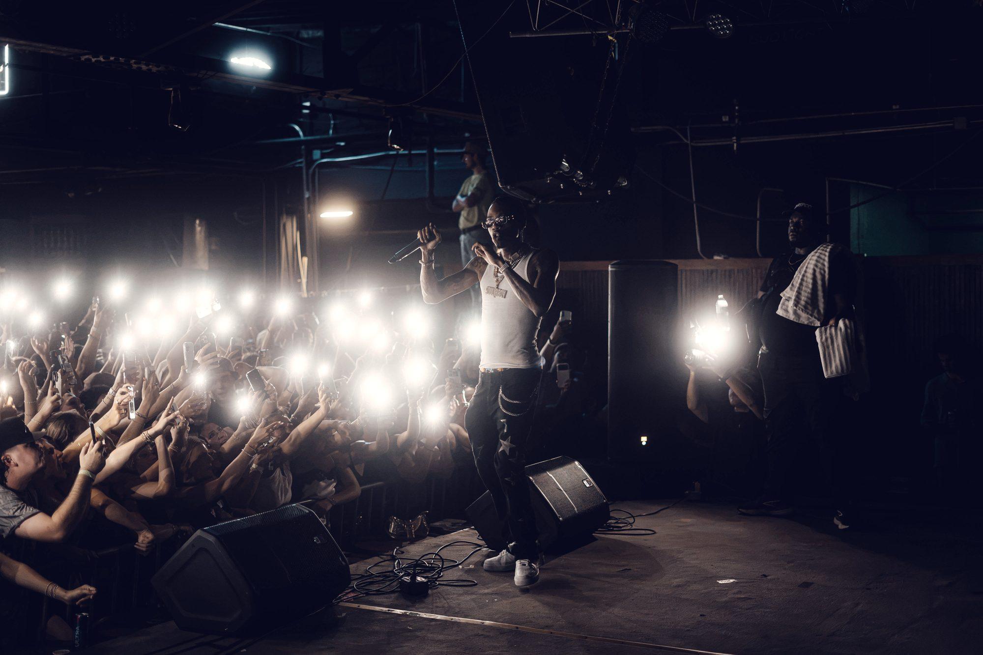 A wide view across the stage with phone lights raised the whole width of the room.